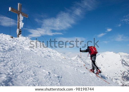 Man on ski reaching the summit in the Alps