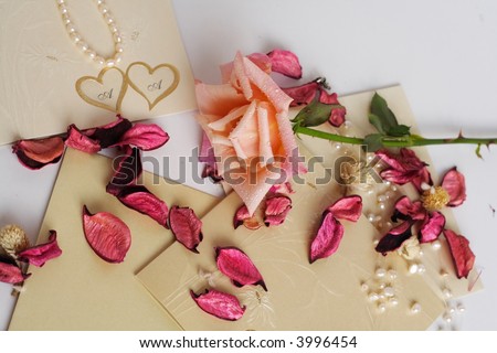 Elegant setup with wedding invitations, pearl necklaces and roses