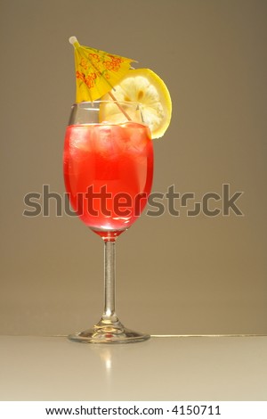 Colorful alcoholic cocktail in a tall glass with lemon and umbrella  against white background