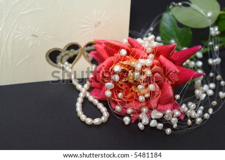 Elegant setup with wedding invitation, pearl necklaces and rose