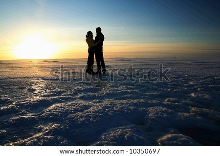 stock photo : Couple holding hands against sunset on frozen sea in Finland