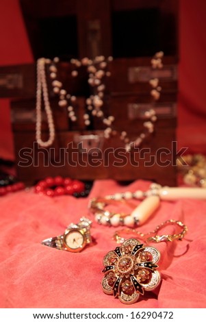 Beautiful golden brooch on red surface and more jewelry in the background