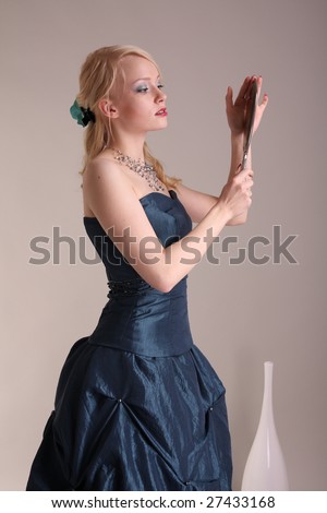 Beautiful young woman wearing a blue prom dress and silver mirror