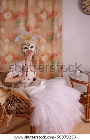 Beautiful model wearing a wedding dress and Venetian mask, studio