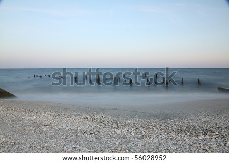 Sea at night with moon and wooden poles