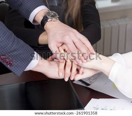 team of three businessmen clasped their hands together, a symbol of teamwork