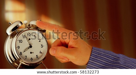 a hand turning off the alarm clock in the early morning