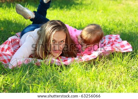 Mom and daughter relaxing in the garden on the green grass