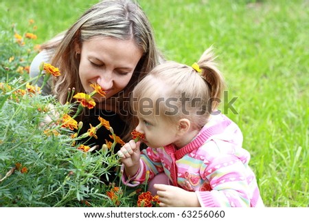 Mom and daughter sniffing flowers in the garden