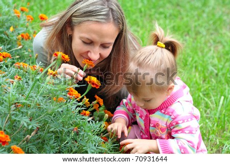 Happy Mom and daughter sniffing flowers in the garden
