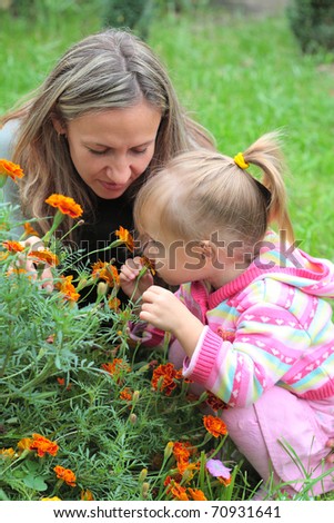 Mom and child sniffing flowers in the garden