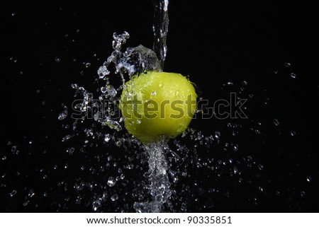 fresh water splash and green apple isolated on black