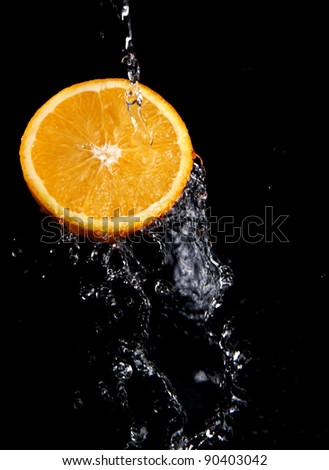 fresh water splash and orange isolated on black.