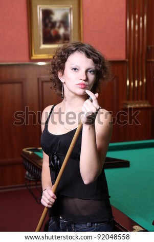 The beautiful blonde aims in the course of game at billiards