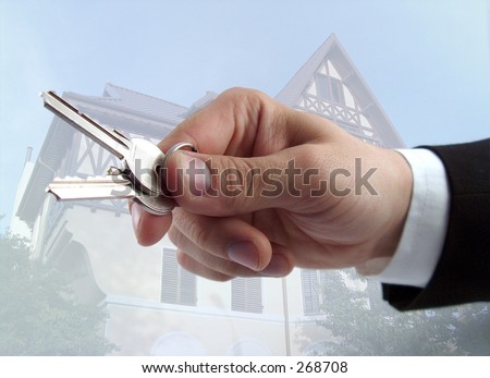 businessman hand offering keys house in the background