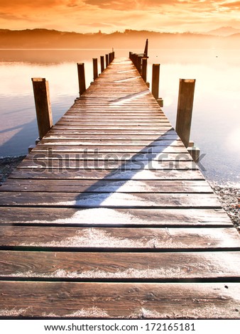 wooden jetty (63) at a little lake in upper bavaria with mountains in background