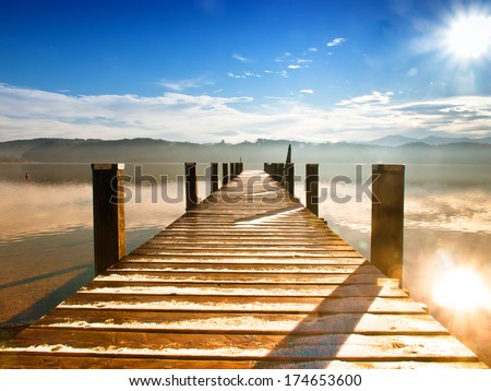 wooden jetty  at a little lake in upper bavaria with mountains in background