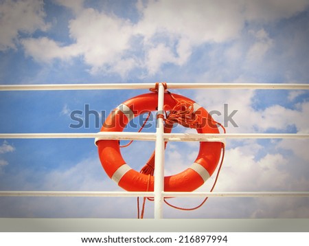 life belt, life buoy, red rescue ring on a ship against blue sky with clouds