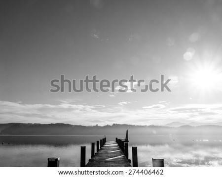 wooden jetty at a little lake in upper bavaria with mountains in background