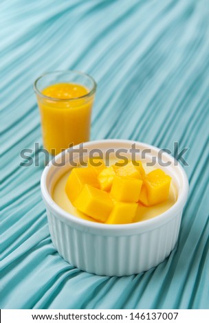 Mango dessert with fresh mango dice and mango puree, on blue tablecloth, space for text