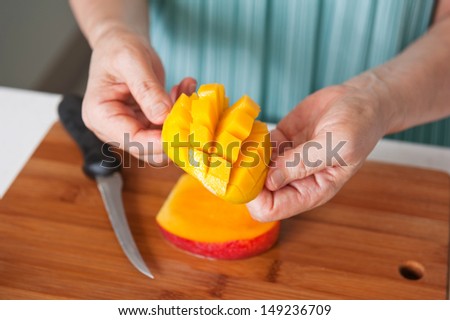 female hands cutting a fresh mango in the kitchen