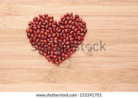 Heart shape by red beans. Common ingredient in Asian cuisine, red beans on wooden background.