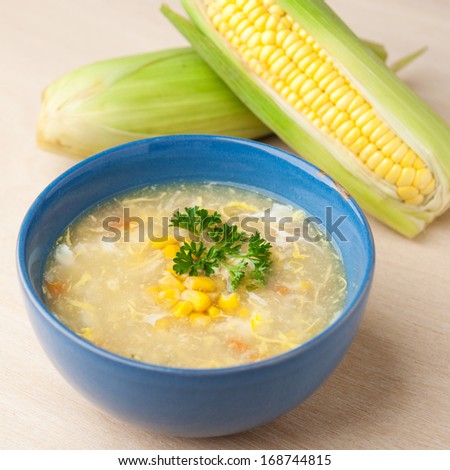 Chinese chicken and corn soup with fresh corn cob on the side.