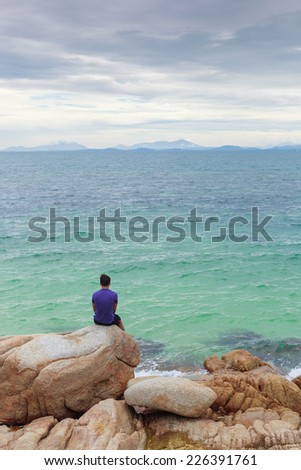 Alone man (lonely) on the rock beside the sea