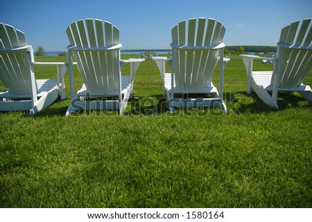 A row of four lawn chairs facing out toward the lake.