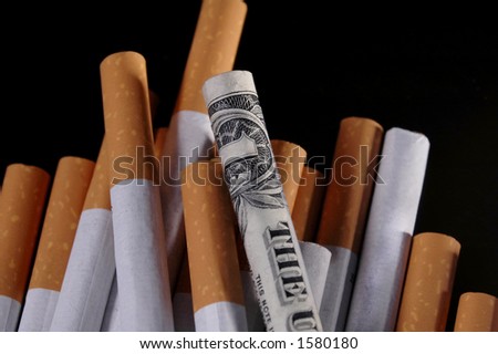 A cigarette wrapped in a dollar bill on a pile of other cigarettes.