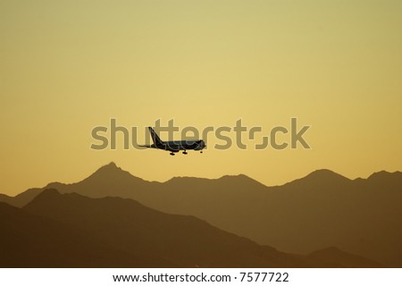 A low-flying plane and mountains are silhouetted at dusk.