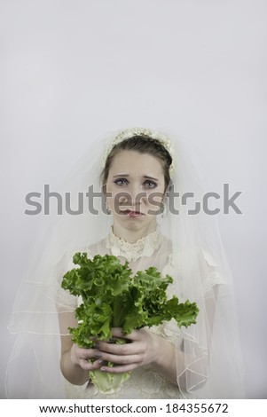 Bride trying to diet holds lettuce instead of bouquet with a sad expression