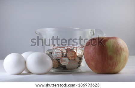 Eggs, an apple, and a measuring cup filled with coins