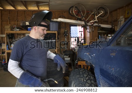Man wearing welding helmet and gloves