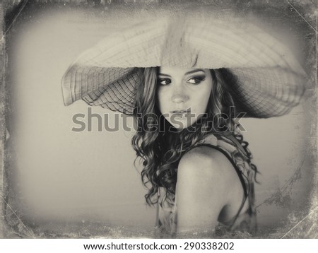 Black and white image of beautiful young woman wearing big sun hat
