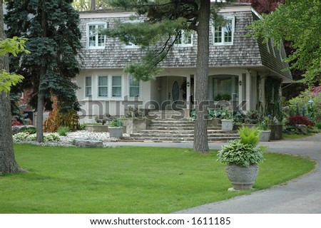 Unusual elegant stucco house with concrete flower urn / planter along driveway