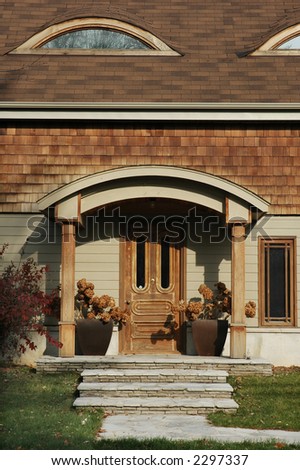Home with lots of wood trim and a wooden front door flanked by two planters