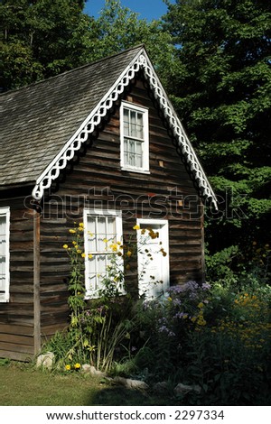 Close up view of wood cabin with pretty overgrown flowers