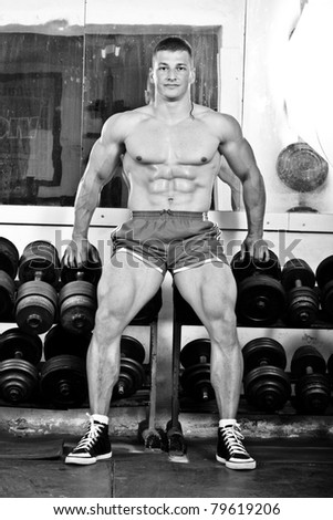 Fitness - powerful muscular man lifting weights in old gym