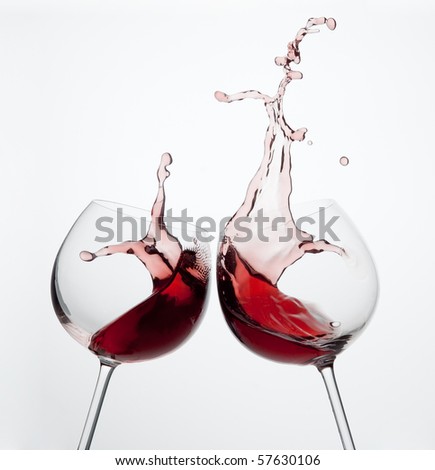 Two wine glasses in toasting gesture with big splashing.