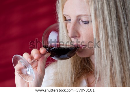 Portrait of a beautiful young woman with a glass of red wine. She tastes wonderful red wine.