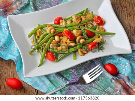 Green beans with mushrooms and tomatoes on a plate.