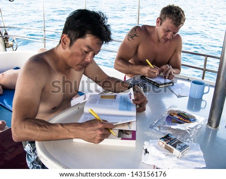 KHAO LAK, THAILAND - NOVEMBER 3: Scuba diving students studying on a dive boat in Similan Islands on November 3, 2010 . Similan Islands are Thailand's most popular diving destination.