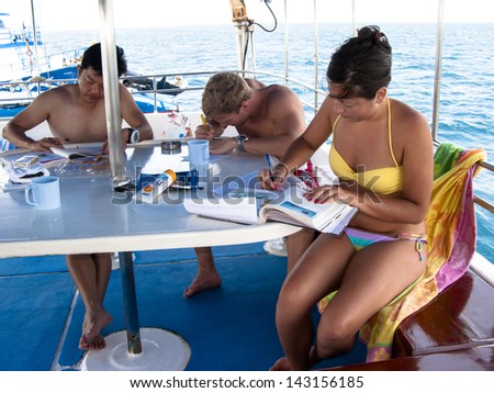 KHAO LAK, THAILAND - NOVEMBER 3: Scuba diving students studying on a dive boat in Similan Islands on November 3, 2010. Similan Islands are Thailand\'s most popular diving destination.