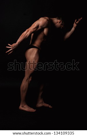 Young attractive man in a black bathing suit bodybuilder with relief muscles