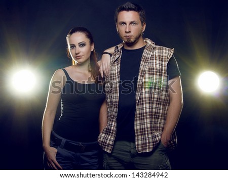 Couple of lovers. Couple of independent steep young people who love each other on a black background with glowing lights (headlights of cars). Both are looking directly into the camera