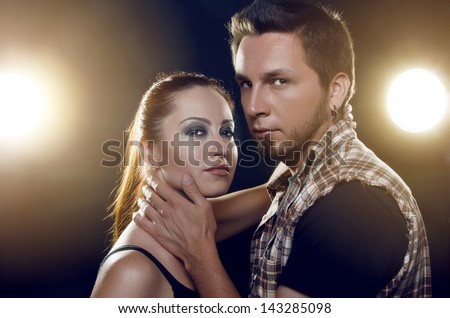 Couple of lovers. Couple of independent steep young people who love each other on a black background with glowing lights (headlights of cars). Both are looking at the camera