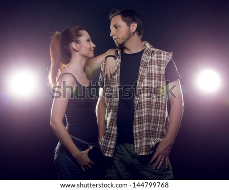 Couple of lovers. Couple of independent steep young people who love each other on a black background with glowing lights (headlights of cars)