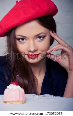Beautiful girl in a red beret. French style. Woman and cake closeup