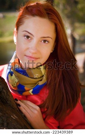 Nice woman in a park in autumn. Dressed in a cape coral